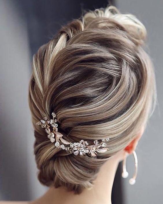 In questa foto un'acconciatura raccolta da sposa con un pettine di fiori di cristalli e foglie colore oro rosa