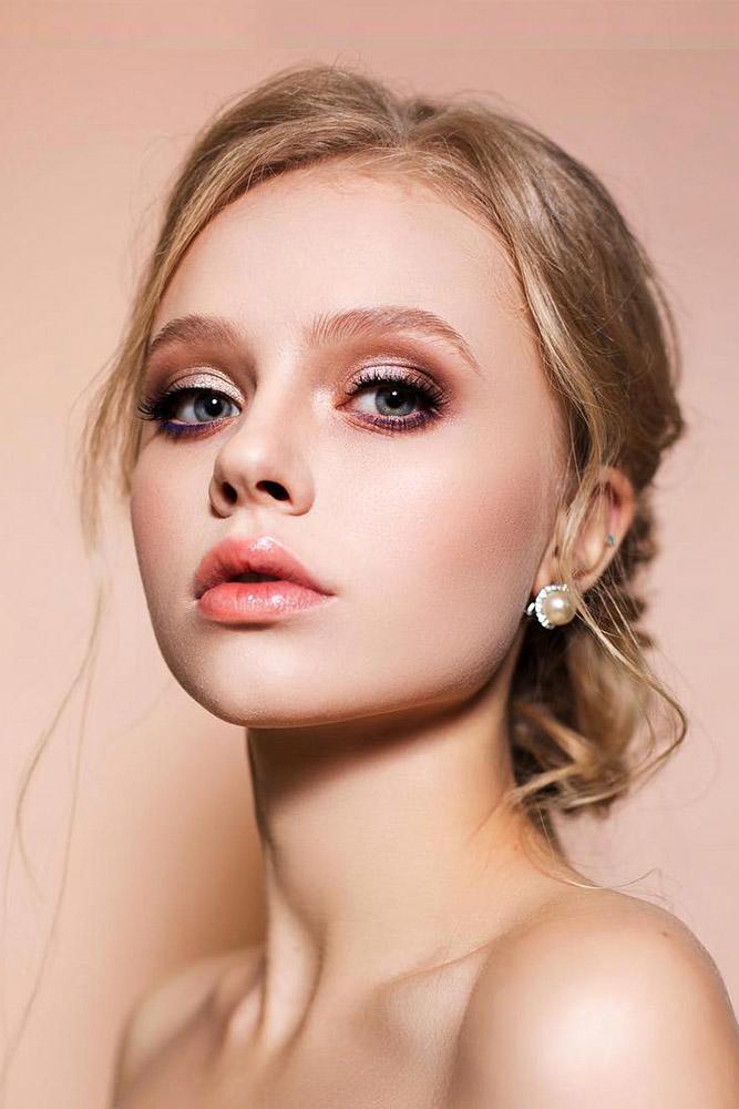 In questa foto una modella con pelle chiara e capelli biondi posa mostrando un trucco sposa nei colori del bronzo glitter. Sulle labbra indossa un gloss rosa lucido