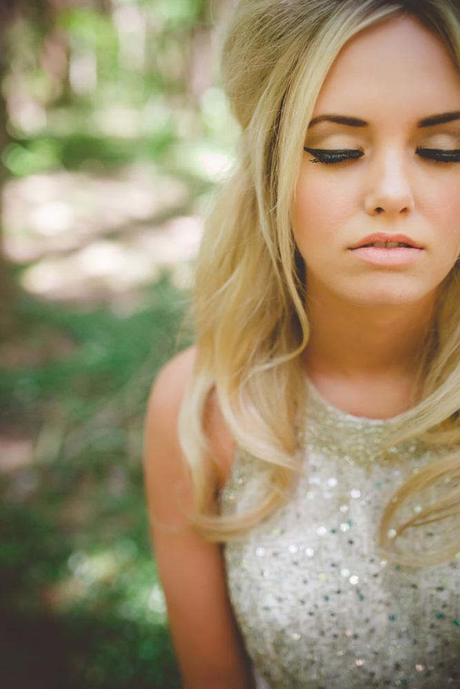 In questa foto una sposa bionda ad occhi chiusi e labbra semiaperte con un look vintage anni 60. Indossa un abito con scollatura halter e un look vintage anni 60 realizzato con un eyeliner nero e rossetto nude  