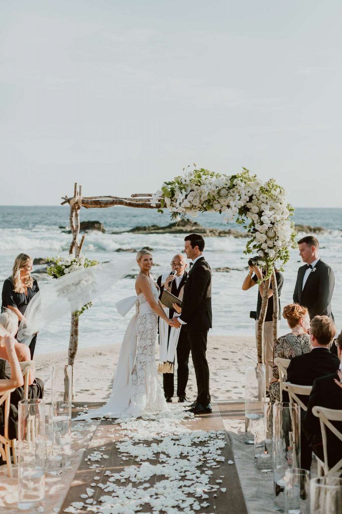 In questa foto una sposa sorridente si volta verso gli invitati durante la cerimonia del suo matrimonio civile in spiaggia