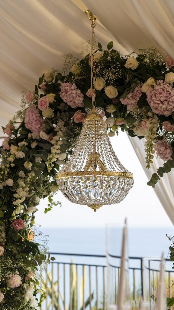 In questa immagine un lampadario di cristallo con sfondo sul mare siciliano