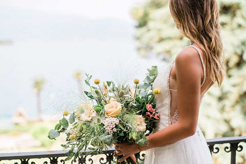 In questa foto una sposa di spalle con un bouquet in mano