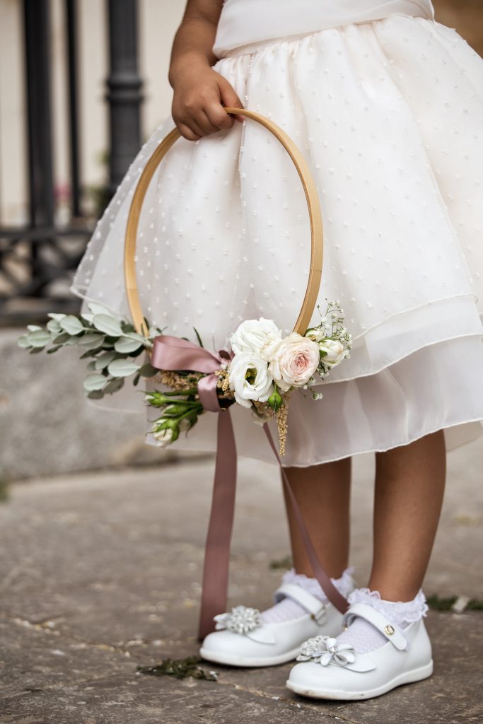 In questa foto il dettaglio di un bouquet di legno chiaro tenuto da una damigella e decorato con fiori bianchi e rosa e foglie di eucalipto