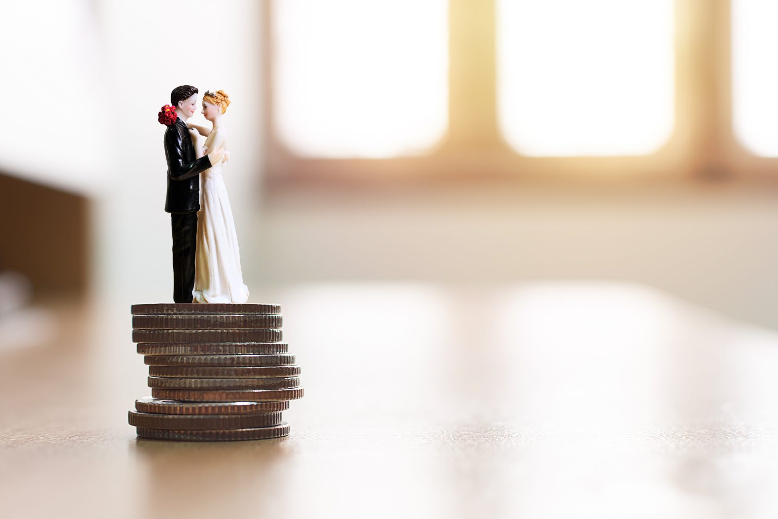 In questa foto una statuina di sposi sopra una pila di monetine