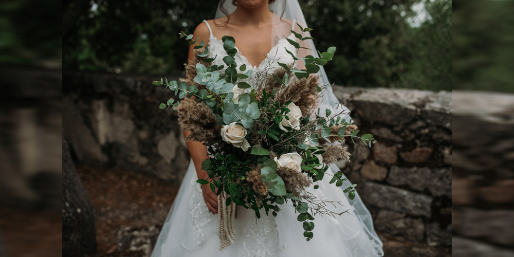 In questa foto di un matrimonio organizzato da Maria Rita Iai, la sposa tiene un bouquet di rose e rami di eucalipto