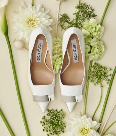 In questa foto un paio di scarpe da sposa Sergio Rossi fotografate dall'alto, tra fiori bianchi e verdi
