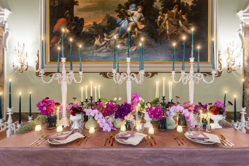 In questa foto un tavolo imperiale allestito per un matrimonio, con fiori e candelabri, all'interno di uno dei saloni affrescati del cinquecentesco NH Collection Palazzo Gaddi, a Firenze