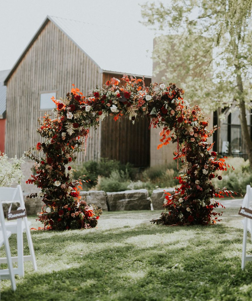 In questa foto un altare per matrimonio civile a forma circolare decorato con foglie e fiori bordeaux, arancioni, bianchi 