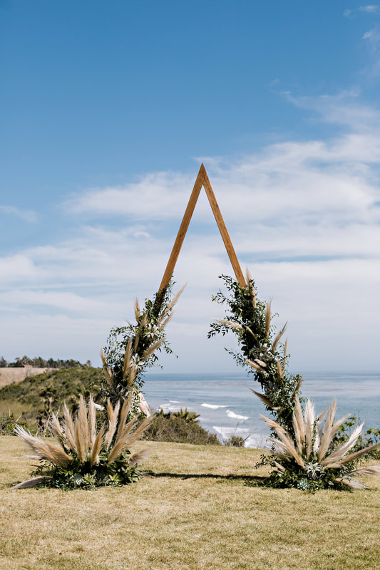 In questa foto l'altare per un matrimonio civile a forma di triangolo decorato con foglie e pampas