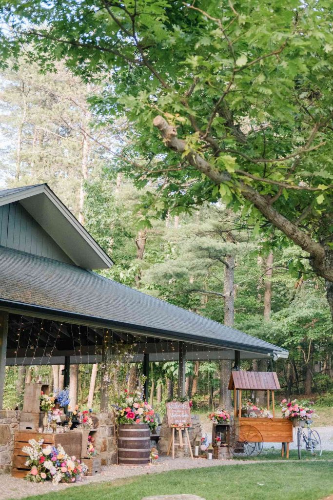 In questa foto allestimenti matrimonio con fiori di campo disposti attorno ad un prato, sul terriccio, su cassette e botti di legno vicino al gazebo che ospita il ricevimento
