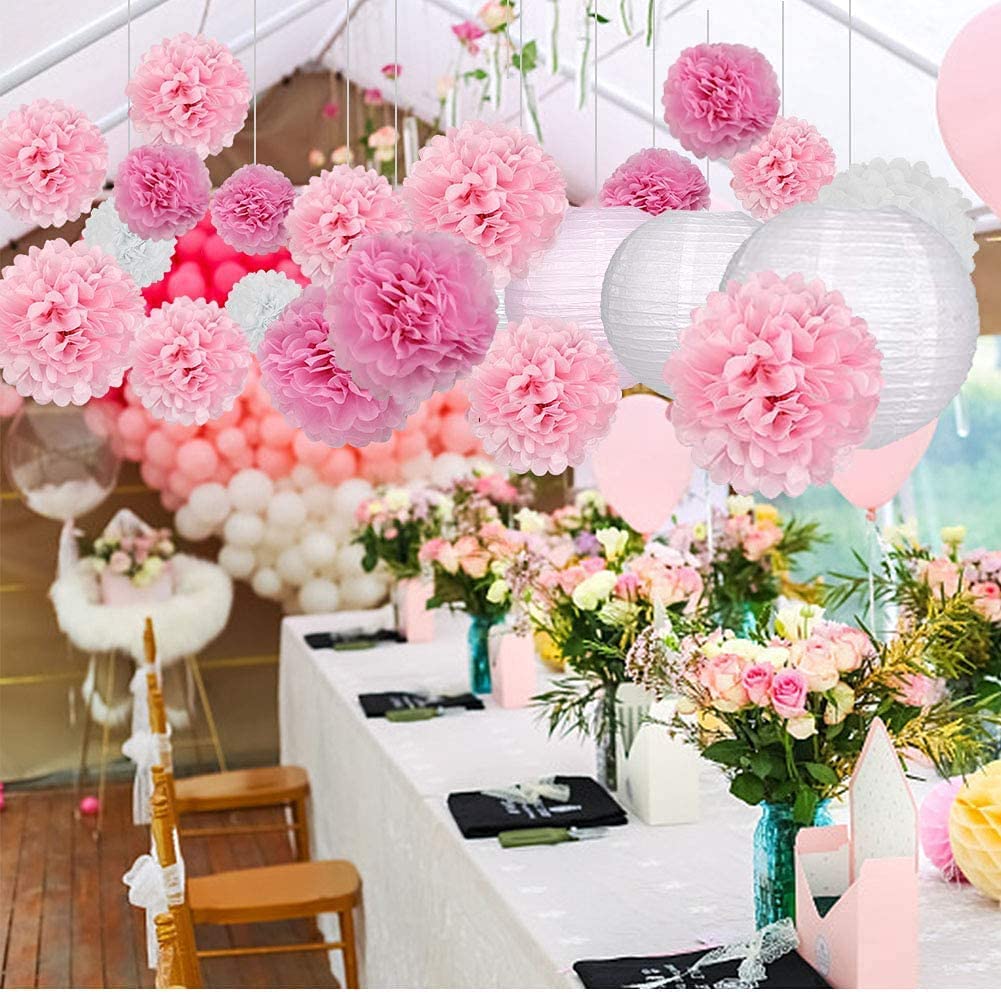 In questa foto allestimenti matrimonio con origami rosa e bianchi a forma di pompon e lanterne cinesi che pendono dal tetto di un gazebo su un tavolo allestito con bouquet di boccioli di rose rosa e bianche