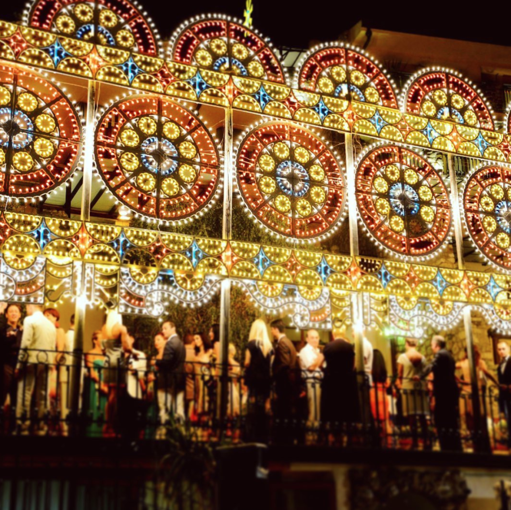 In questa foto luminarie colorate in stile siciliano illuminano la terrazza su cui è organizzato un ricevimento nuziale