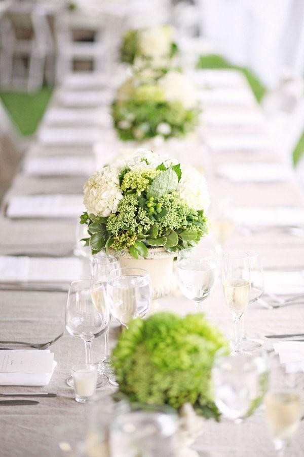 In questa foto centrotavola con vasi di ortensie bianche e verdi, con altri fiori verdi. La mise en place con calici e tovagliato color tortora.  