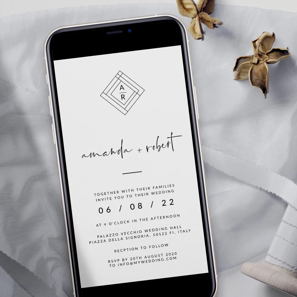 In questa foto uno smartphone con la schermata di un save the date per matrimonio in stile minimal. Lo smartphone è poggiato su un drappo di stoffa bianco, con rocchetti di nastro e due fiori di anice secchi sull'angolo superiore destro