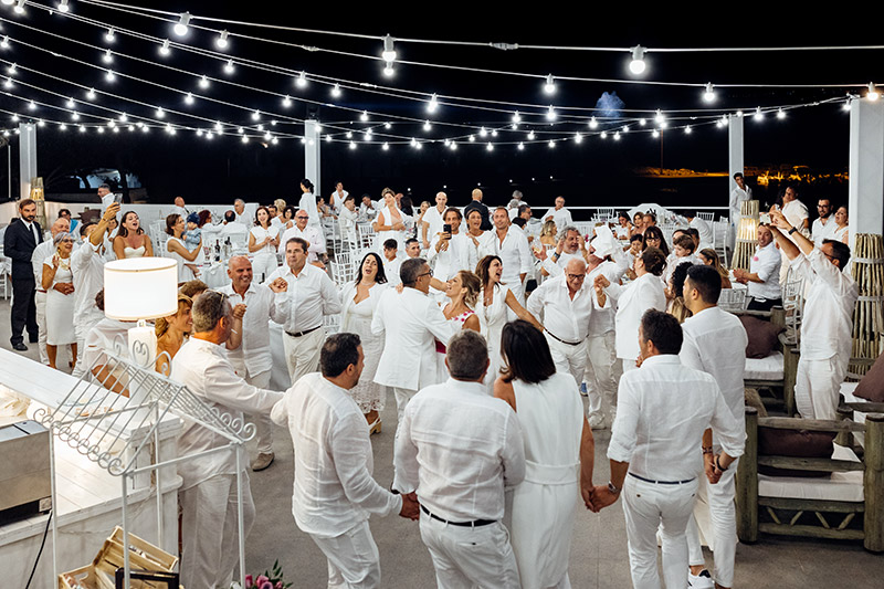 In questa foto sposi e invitati, tutti rigorosamente vestiti di bianco, ballano e si divertono durante il ricevimento nuziale