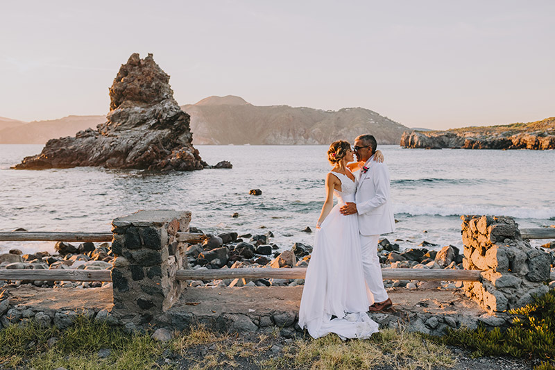 In questa foto gli sposi abbracciati davanti al mare di Vulcano e alle spalle uno dei faraglioni tipici dell'isola