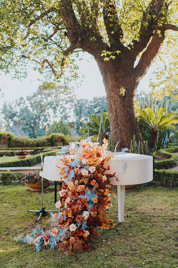 In questa foto un pianoforte bianco è stato allestito con decori floreali che riprendono il tema autunnale delle nozze