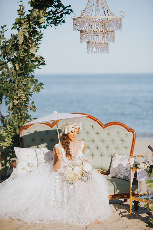 In questa foto un lampadario chandellier sulla spiaggia e complementi d'arredo dal gusto vintage per un photo booth ricercato 