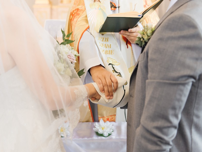 In questa foto due sposi davanti all'altare davanti al sacerdote che impone una mano su di loro dopo il processetto