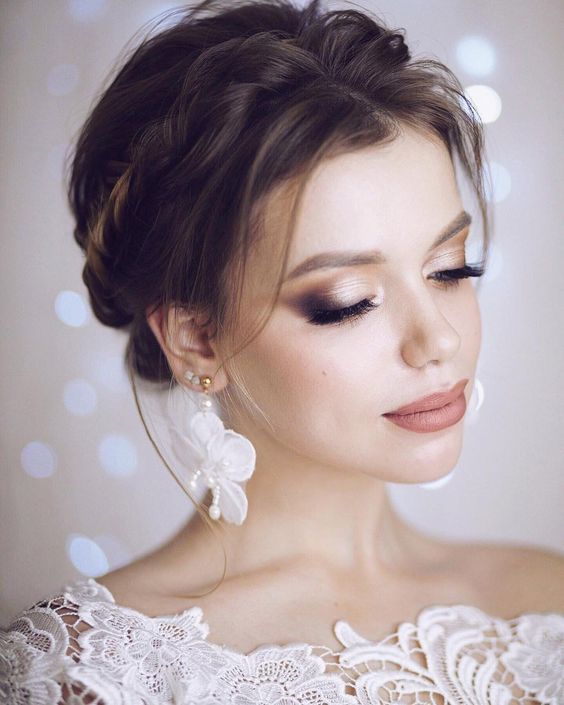 In questa foto una sposa con un trucco elegante. Sugli occhi chiusi mostra un ombretto perlato sfumato con un ombretto più scuro. Sulle labbra indossa un rossetto nude