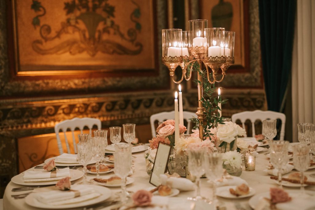 In questa foto una mise en place elegante con un candelabro al centro e rose rosa 