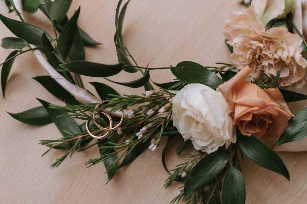 In questa foto un hoop bouquet con rose bianche e rosa a cui sono legate le fedi degli sposi