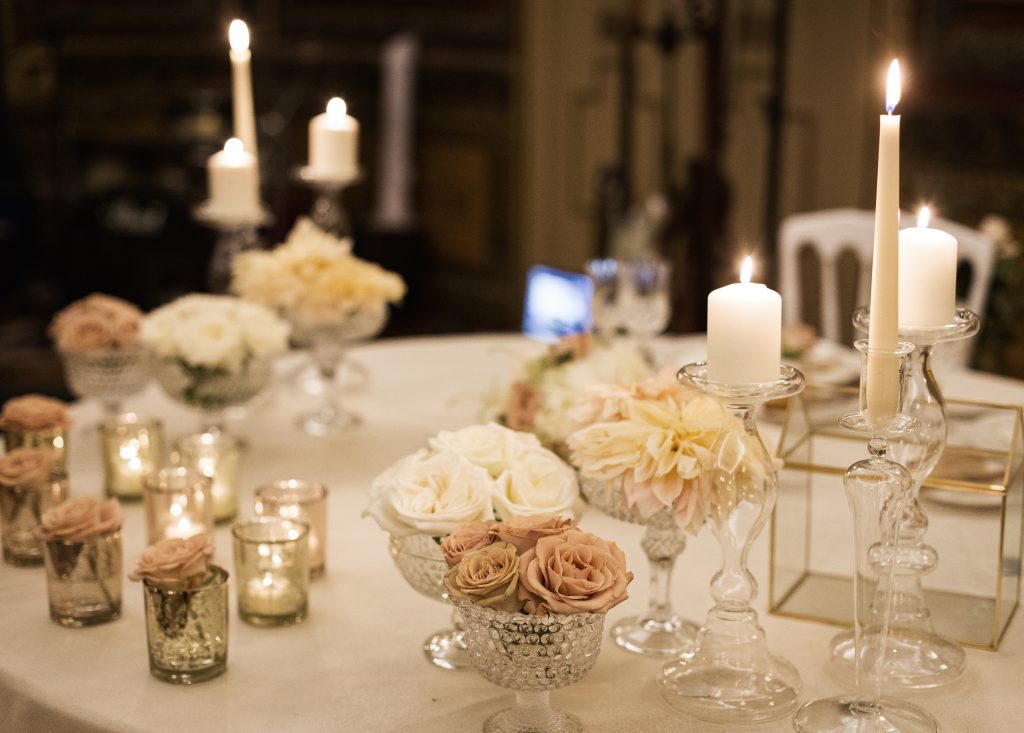 In questa foto una mise en place romantica con vasi di cristallo con fiori rosa e bianchi