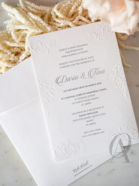 Nella foto, partecipazioni matrimonio eleganti con busta e invito bianco, arricchito da decori embossati 