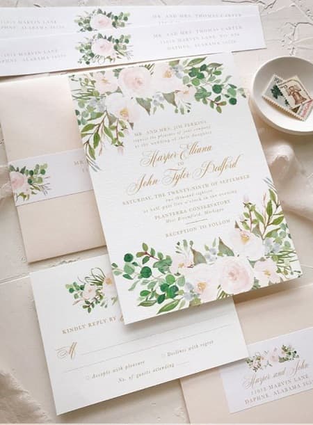 Nella foto, partecipazioni matrimonio eleganti con invito bianco e decori floreali in toni delicati e busta da lettera classica in colore rosa cipria