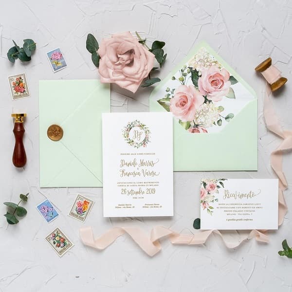 In questa foto, inviti per matrimonio eleganti con busta da lettera classica in verde menta chiaro decorata all'interno con grandi rose rosa e chiusa con sigillo di ceralacca oro