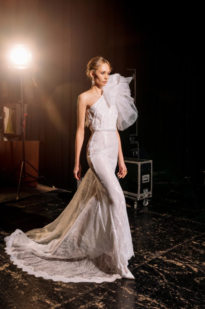 In questa foto una modella indossa un vestito da sposa monospalla a sirena di Bencivenga, tra gli abiti da sposa 2022 più belli