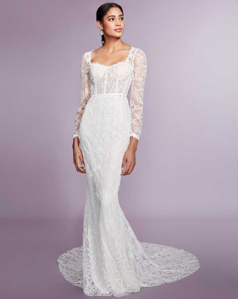 In questa foto una modella indossa un abito da sposa con le maniche 2022 della collezione Marchesa. L'abito è a sirena e ha delle maniche lunghe di pizzo.