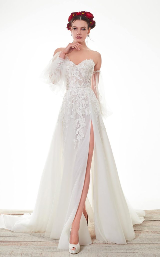 In questa foto una modella indossa un abito da sposa con le maniche 2022 della collezione Sofia haute couture. L'abito ha un decoro floreale sul corsetto e delle maniche rimovibili di velo.