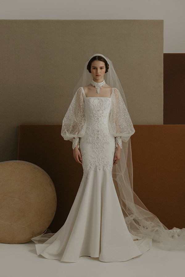 In questa foto una modella indossa un abito da sposa con le maniche 2022 della collezione The Atelier Couture. Il vestito è a sirena con delle ampie maniche baloon riccamente decorate.