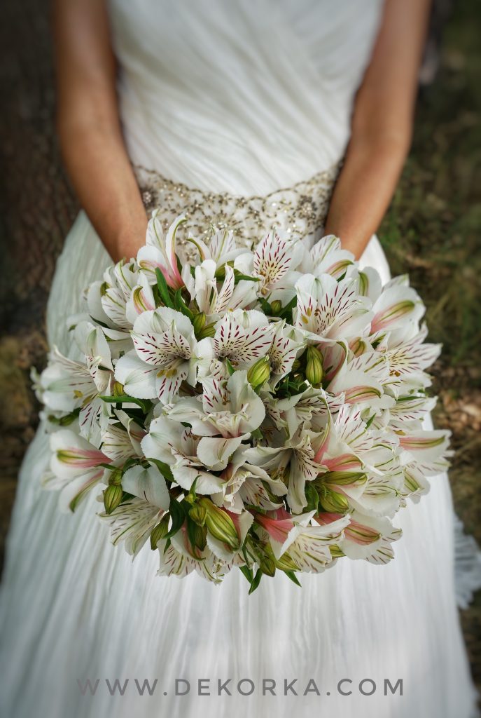 In questa foto le mani di una sposa che tiene un bouquet di alstroemeria 