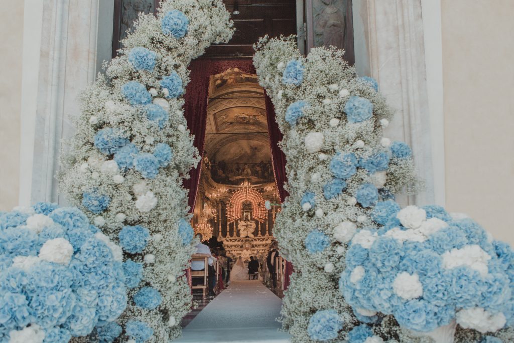 In questa foto l'ingresso di una chiesa decorata con ortensie celesti e nebbiolina