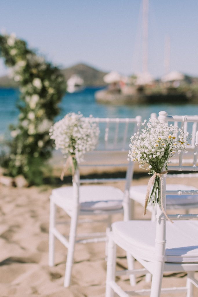 In questa foto il dettaglio di mazzolini di fiori per matrimonio di nebbiolina legati a delle sedie chiavarine bianche  usate per una cerimonia civile su una terrazza sul mare