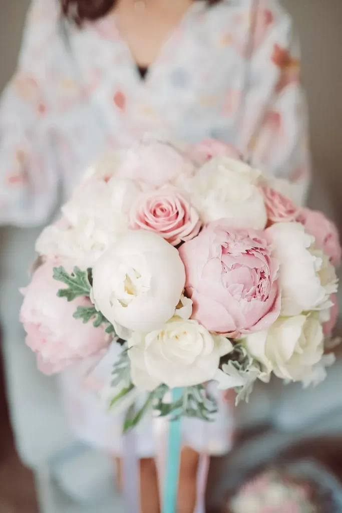 In questa foto un bouquet da sposa con peonie rose e bianche e rose nei colori rosa e bianco