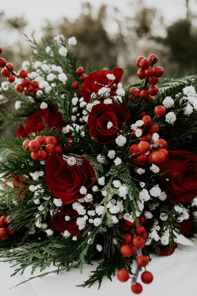 In questa foto il dettaglio di una composizione di fiori per matrimonio con rose rosse, bacche rosse e nebbiolina