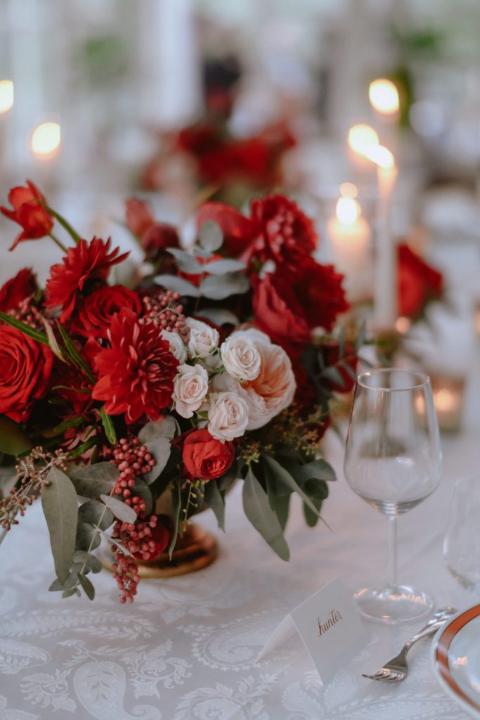 In questa foto il dettaglio di una tavola natalizia decorata con centrotavola di rose e gerbere rosse e roselline rosa