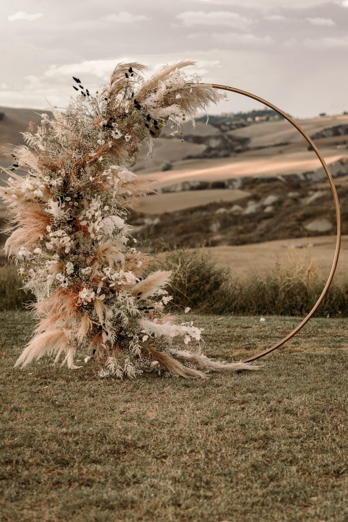 In questa foto una struttura circolare colore oro decorata con pampas e felce