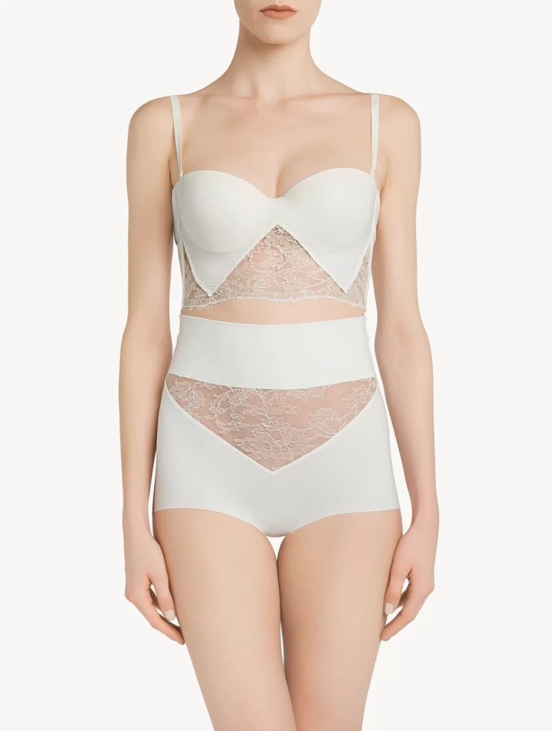 In questa foto un completo di intimo contenitivo con culotte a vita alta e reggiseno con fascia modellante di colore bianco