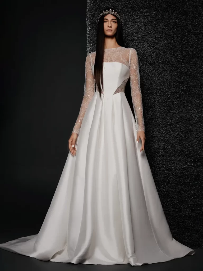 In questa foto una modella posa indossando un abito da sposa redingote di Vera Wang con maniche lunghe e trasparenti glitter 