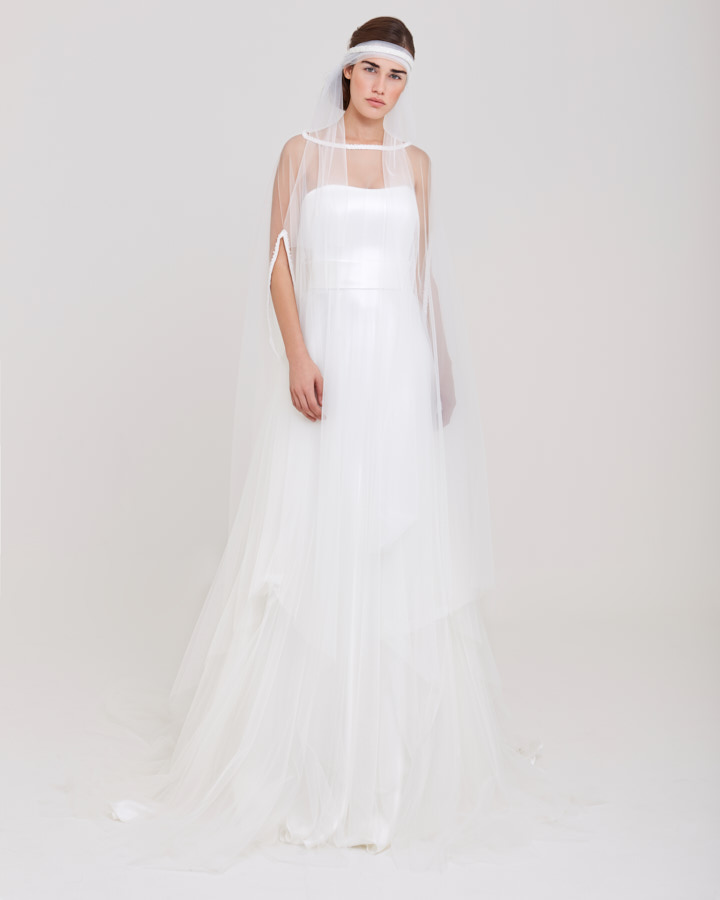 In questa foto una modella posa indossando un abito da sposa trasformabile di Angela Pascale scivolato con cappa removibile in tulle di seta sulle spalle
