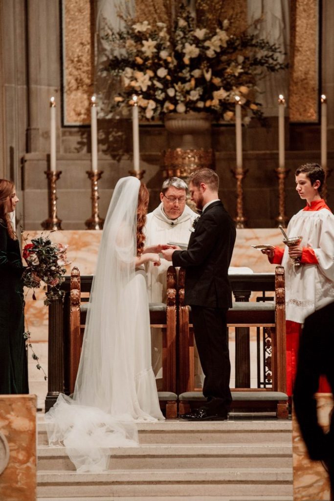 In questa foto due sposi si scambiano le promesse in chiesa davanti al sacerdote durante il rito del matrimonio