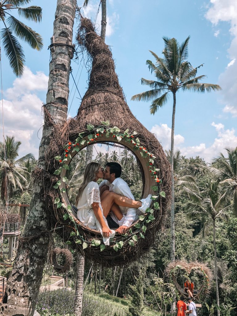 In questa foto una coppia di sposi si bacia dentro ad un grande nido di paglia durante il loro viaggio di nozze a Bali