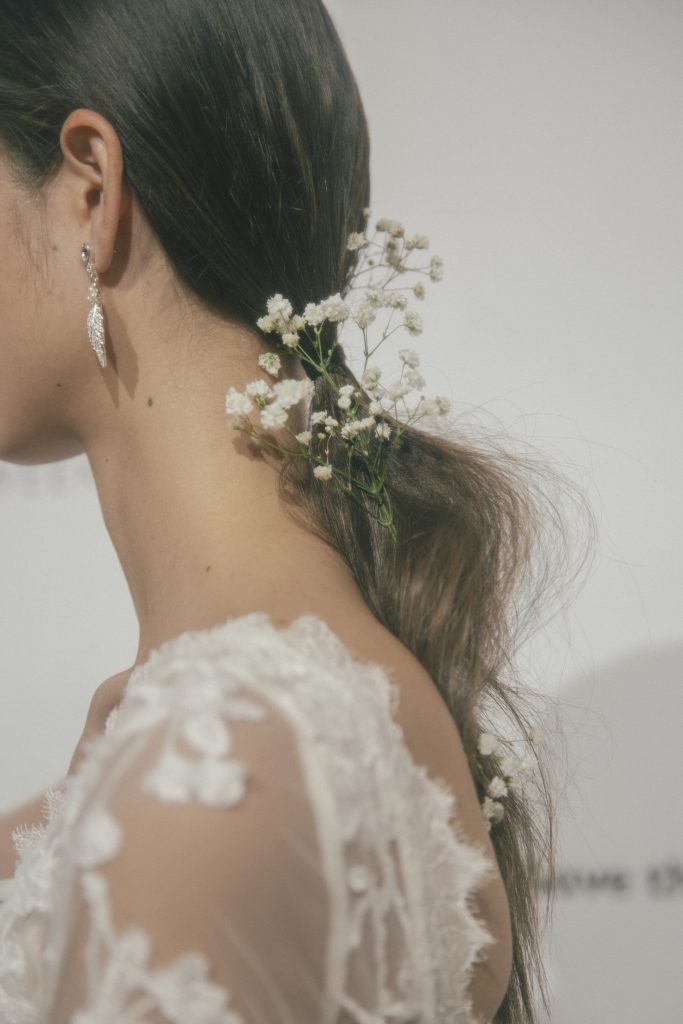 In questa foto una modella ha i capelli raccolti in una coda legata con un mazzolino di gypsophila bianca