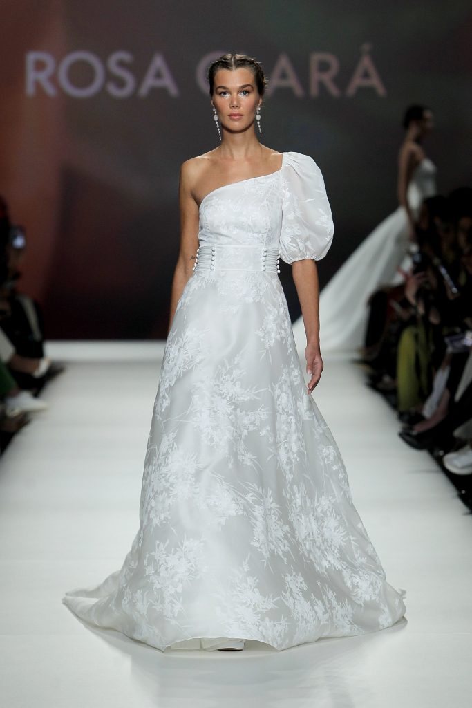 In questa foto una modella indossa un abito da sposa Rosa Clarà 2023, visto sulla passerella della BBFW 2022