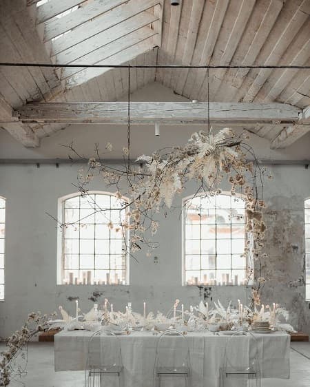 In questa foto, composizioni pensili e un lungo centrotavola total white sono i protagonisti dello stile fiori matrimonio industriale 
