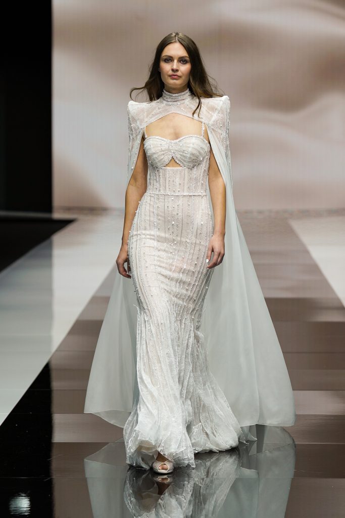 In questa foto la modella indossa un abito da sposa della collezione sposa Michela Ferriero 2023 con mantella a sirena.